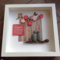 a shadow box with some rocks and flowers in it