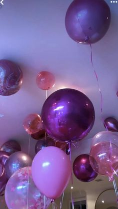 purple and pink balloons are hanging from the ceiling