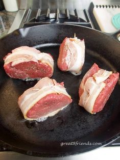 four pieces of meat are being cooked in a skillet