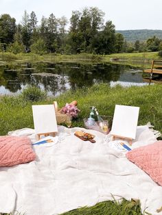 two empty canvases are set up on the grass near a pond and picnic table