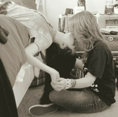 a woman sitting on the floor kissing her cat