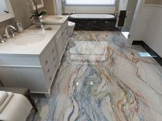 a bathroom with marble flooring and white fixtures in the bathtub, sink, and toilet