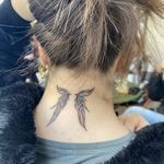 the back of a woman's neck with a small tattoo on her left side