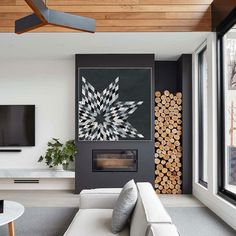 a modern living room with white furniture and wood pieces on the wall, along with a large flat screen tv