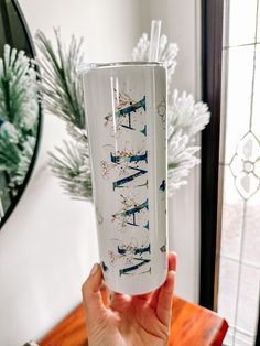 a person holding up a white glass with blue writing on it