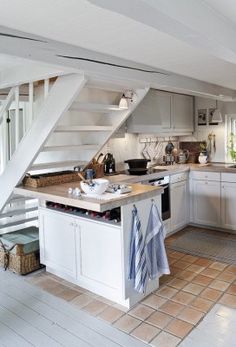 a kitchen with white cabinets and an open staircase leading up to the upper floor area