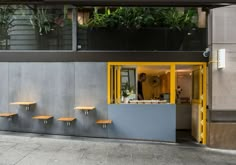 the outside of a restaurant with yellow and gray benches