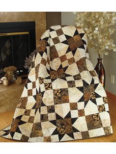 a black and white quilt sitting on top of a chair next to a fire place