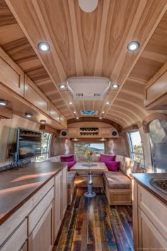 an interior view of a camper with wood paneling and purple pillows on the couch