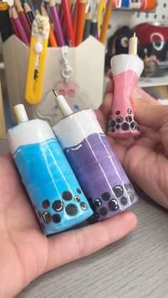 three different colored lighters in the palm of someone's hand with pencils