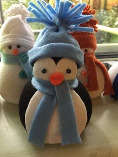 three stuffed penguins wearing hats and scarves on a window sill in front of a window