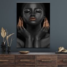 a woman with her hands on her face in front of a black and gold painting