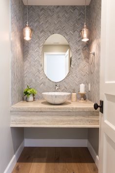 a bathroom with a sink, mirror and lights on the wall next to wood flooring