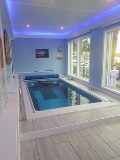 an indoor swimming pool with blue lighting and tile flooring in the middle of a room