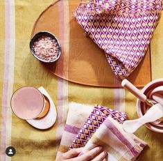 a person is using a cloth to clean dishes on a table with bowls and spoons