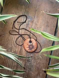 a wooden table topped with a brown pendant and green plant life on top of it