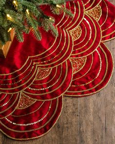 three red place mats with gold designs on them and a christmas tree in the background