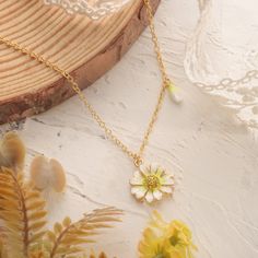 Step into a world of whispered secrets and timeless charm with the Daisy Pendant Necklace, part of our Nature Jewelry collection. Meticulously handcrafted in 18K gold-plated brass, the delicate enamel daisy sparkles with cubic zirconia accents, a nod to the Victorian Era’s love for symbolism. Back then, daisies weren’t just flowers—they represented innocence, loyalty, and the sacred duty of keeping confidences. Gifting a daisy meant, in the silent language of flowers, “your secret is safe with m Silent Language, Brass Pendant Necklace, Daisy Pendant, Daisy Necklace, Golden Necklace, Language Of Flowers, Brass Pendant, Nature Jewelry, Flower Jewellery