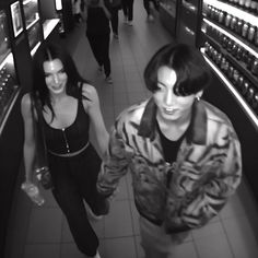 two women are walking down the aisle of a liquor store, one in black and white