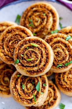 several cinnamon rolls on a white plate with green garnish and sprinkles