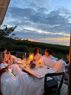 a group of people sitting around a table with food and drinks on top of it