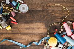 sewing supplies laid out on top of a wooden table next to thread and spools