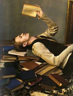 a man laying on top of a pile of books