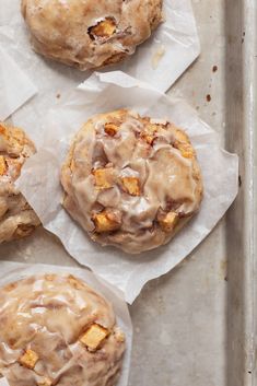 four cinnamon rolls with icing on some parchment paper