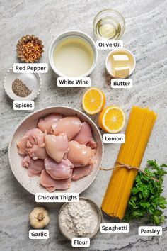 ingredients to make chicken broth laid out on a marble counter top, including carrots, parsley, garlic, lemon, and pepper