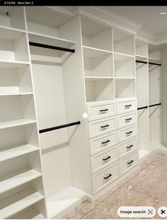 an empty walk in closet with white shelves and drawers