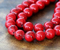 red beads are lined up on a wooden surface