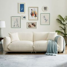 a living room with white furniture and pictures on the wall