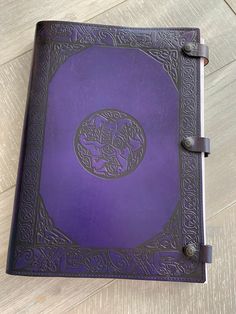 a purple leather book with an intricate design on the front cover and two metal handles