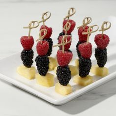 some fruit is sitting on a white plate with gold letters and black raspberries