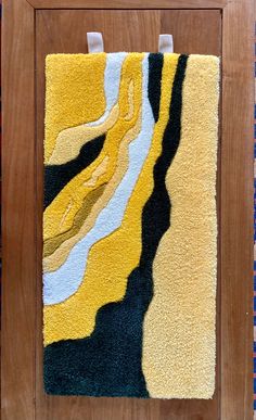 a yellow and black rug hanging on a wooden frame