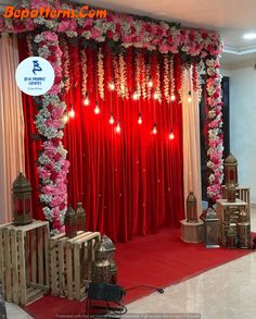 the stage is decorated with red curtains and white drapes, lanterns and flowers on it