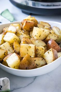 a white bowl filled with potatoes on top of a table