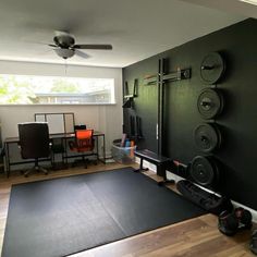 a home gym with black walls and hard wood flooring