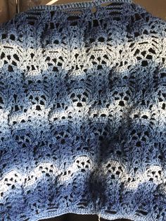 a blue and white crocheted blanket sitting on top of a table