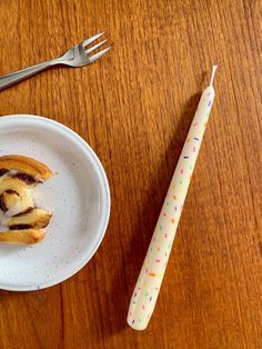 a plate with a pastry on it next to a fork and knife, sitting on a wooden table