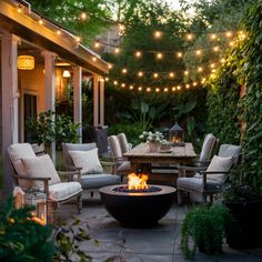 a fire pit sitting in the middle of a patio surrounded by chairs and tables with lights strung over it