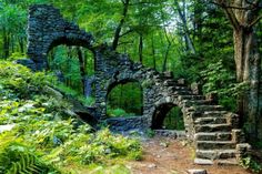 an old stone building in the woods with stairs leading up to it's entrance