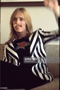 a woman sitting on top of a couch wearing black and white striped clothing with her hands in the air