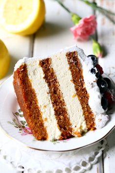 a slice of cake with white frosting and blueberries on a plate next to lemons