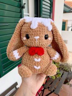 a hand holding a small brown stuffed animal