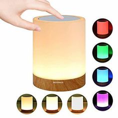 a person is touching the light on top of a wooden table with four different colors