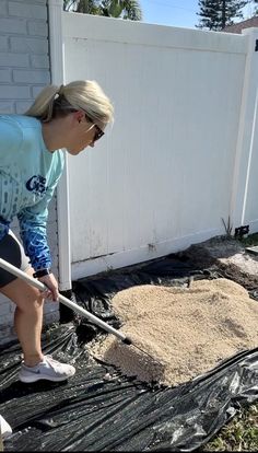 a woman is shoveling sand into the ground