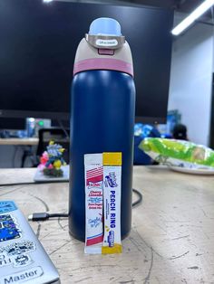 a blue water bottle sitting on top of a wooden table next to a remote control