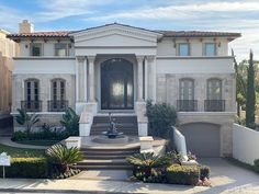 a large white house with a fountain in the front yard