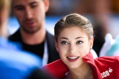 a woman in a red jacket is talking to some other people while she looks at the camera